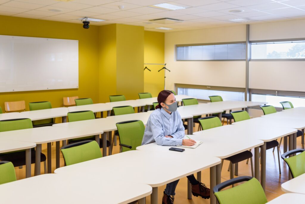 Woman in face mask in empty classroom